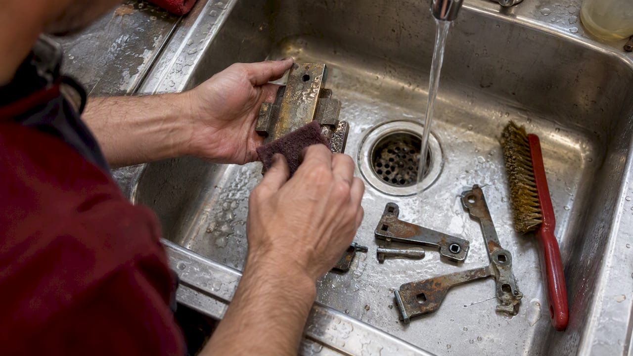 Rusty mortise lock parts beside cleaning brush